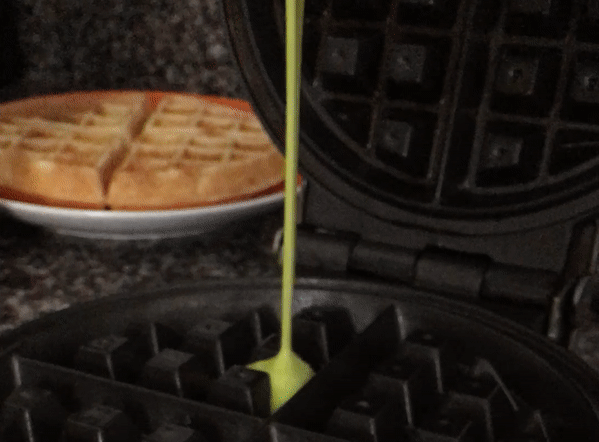 Making Rainbow Belgian Waffles. Pour batter with food coloring onto hot waffle maker